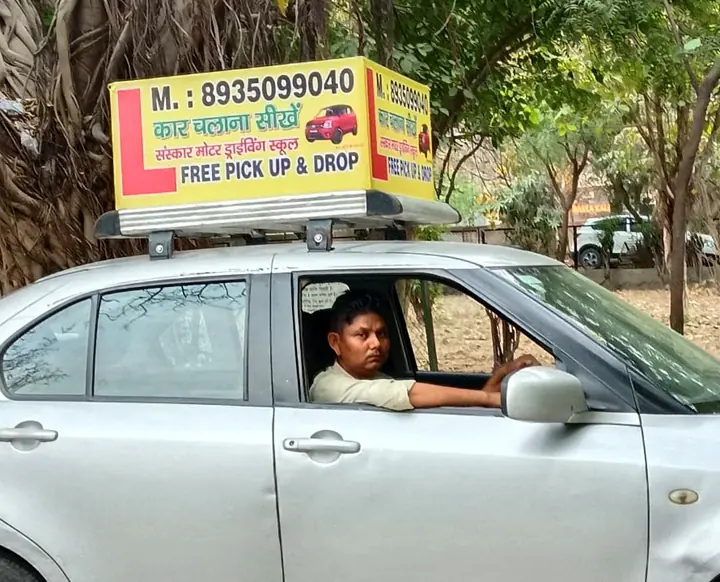 The Sanskar Motor training car on a Dwarka road, with the yellow driving school board on its roof